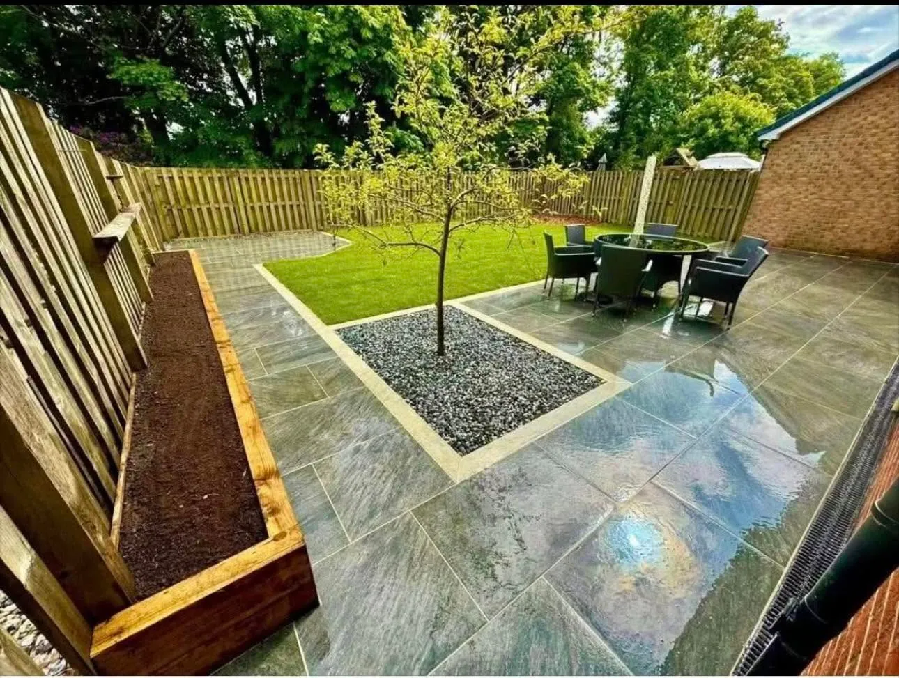 Slate patio with raised sleeper planter and lawn feature